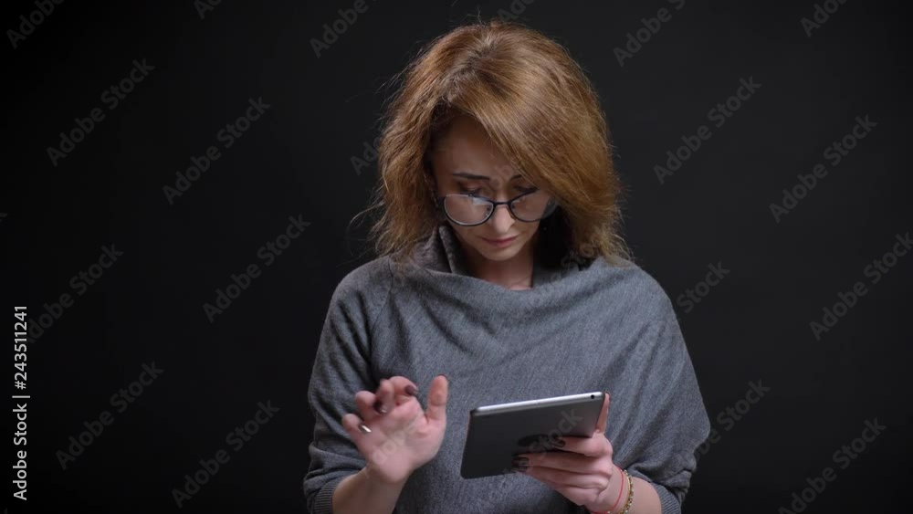 Closeup portrait of attractive adult woman browsing internet on the tablet casually then looking at cameraman and smiling