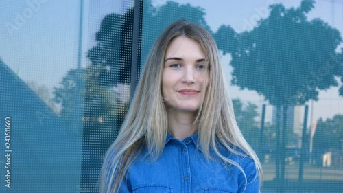Charming young woman with a magnificent long blond hair and blue eyes turns to camera and smiles
