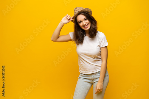 Excited young woman in white t-shirt, widely smiling, looking at camera. Isolated on yellow background