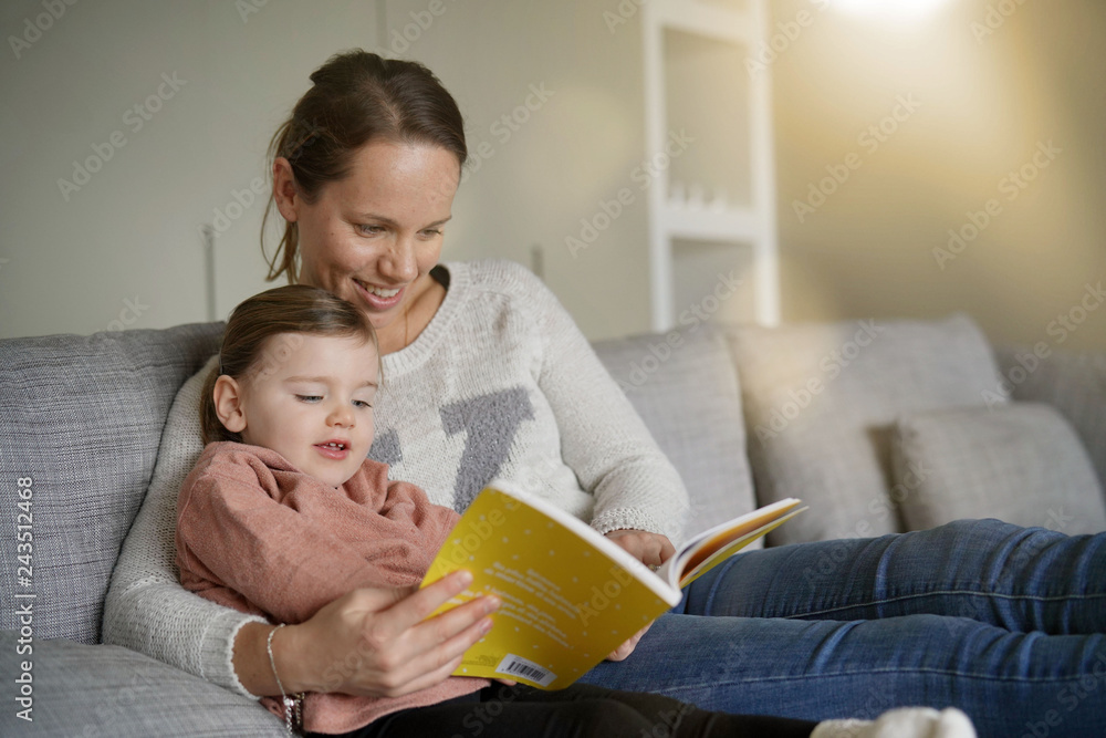 Mother and young daughter reading a story together at home
