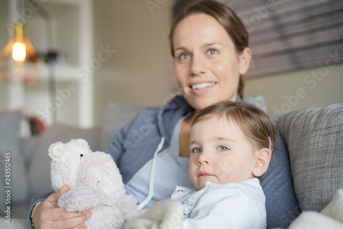 Mother and daughter relaxing on sofa looking out into distance