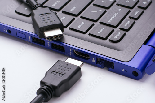 Two ends of the HDMI cable near the HDMI port of the modern blue laptop on a white background photo