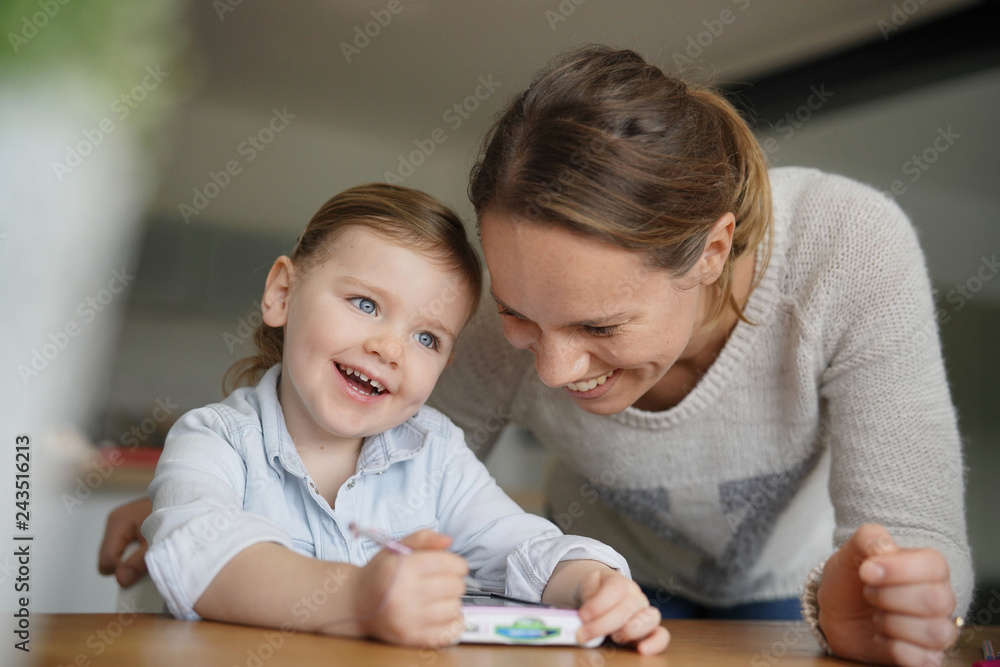 Mother and daughter having fun playing with child's tablet at home Mother and daughter having fun playing with child's tablet at home