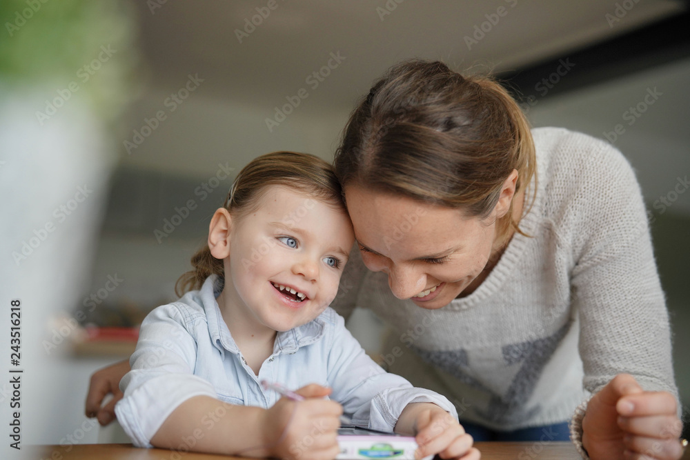 Mother and daughter having fun playing with child's tablet at home Mother and daughter having fun playing with child's tablet at home