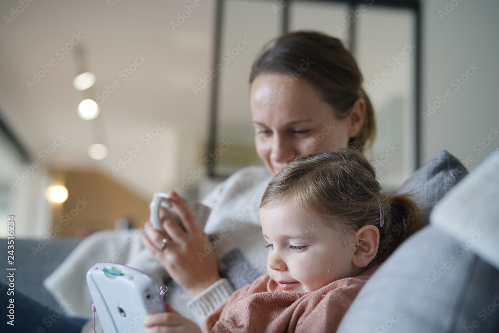 Mother and young daughter playing games on child's tablet at home Mother and young daughter playing games on child's tablet at home