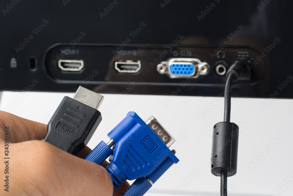 Man`s hand holds HDMI and VGA cables against a monitor with ports. Choise  between modern HDMI and old VGA connection Stock Photo | Adobe Stock