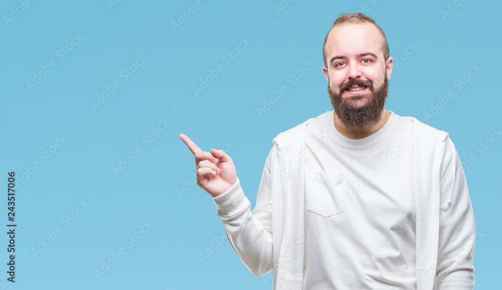 Young caucasian hipster man wearing sport clothes over isolated background with a big smile on face, pointing with hand and finger to the side looking at the camera. Young caucasian hipster man wearing sport clothes over isolated background with a big smile on face, pointing with hand and finger to the side looking at the camera.