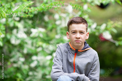 Portrait of serious boy in summer park.