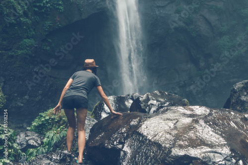 Young woman posing on a great Sekumpul waterfall in the deep rainforest of Bali island, Indonesia.