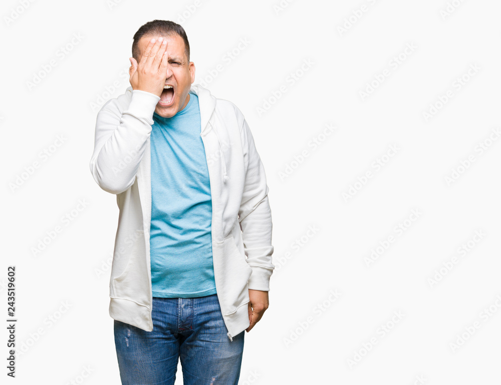 Middle age arab man wearing sweatshirt over isolated background covering one eye with hand with confident smile on face and surprise emotion. Middle age arab man wearing sweatshirt over isolated background covering one eye with hand with confident smile on face and surprise emotion.