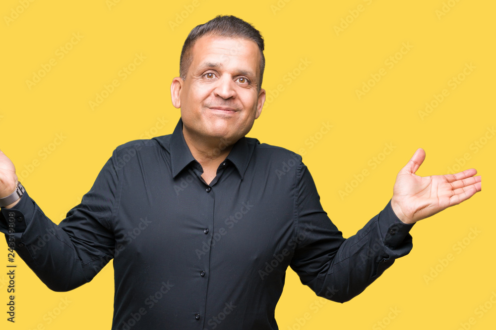 Handsome middle age arab business man over isolated background clueless and confused expression with arms and hands raised. Doubt concept.