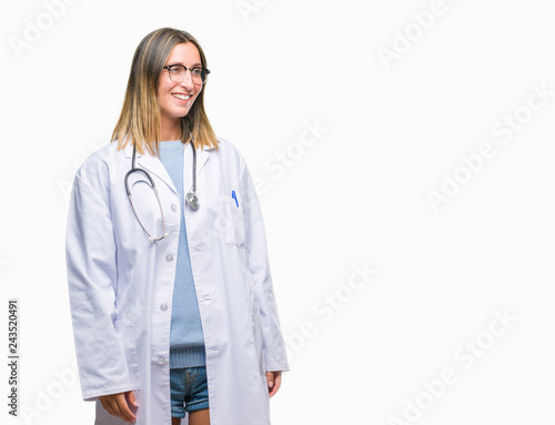 Young beautiful doctor woman headphones over isolated background looking away to side with smile on face, natural expression. Laughing confident.