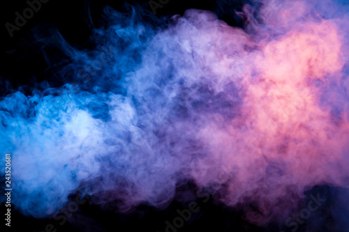 Multicolored smoke from a vape of blue and purple color of the strange mystical form on on a black isolated background. Bright clouds in the abstract form.