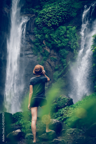 Young woman posing on a great Sekumpul waterfall in the deep rainforest of Bali island  Indonesia.