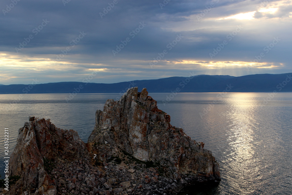 Dusk landscape with Shaman Rock or Cape Burkhan at the Olkhon Island on Baikal lake. Summer vacation in the heart of Siberia. The sacred place of Buddhists and shamans. Small sea Dusk landscape with Shaman Rock or Cape Burkhan at the Olkhon Island on Baikal lake. Summer vacation in the heart of Siberia. The sacred place of Buddhists and shamans. Small sea