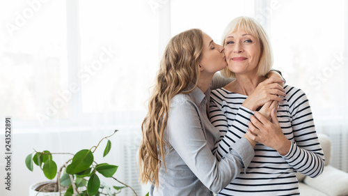 Young daughter kissing senior mother on the cheek