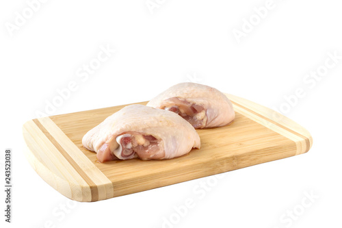 Raw chicken thighs on cutting board, on a white background.