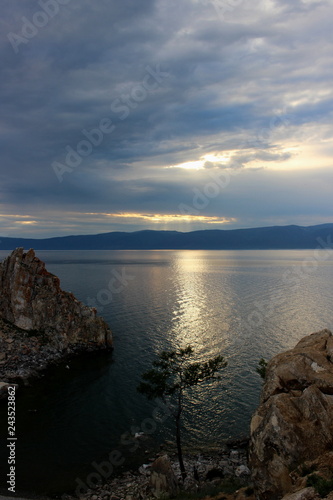 Dark landscape of the last colors of the evening on Cape Burkhan at the Olkhon Island on Baikal lake. Summer vacation in the heart of Siberia. The sacred place of Buddhists and shamans. Small sea