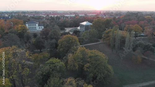 Fly over a citypark at sunset autumn with colorful trees and a river behind the park. photo