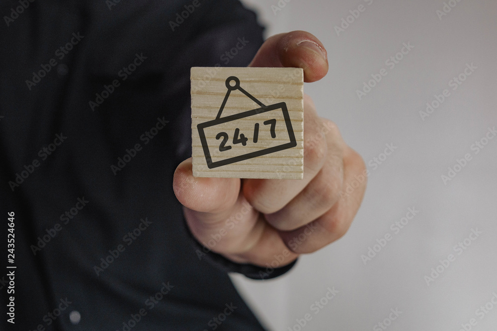 wooden cube in the hand of a man with the inscription 24/7 wooden cube in the hand of a man with the inscription 24/7