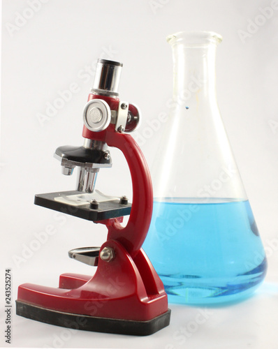 Microscope and erlenmeyer flask with blue liquid isolated on white background