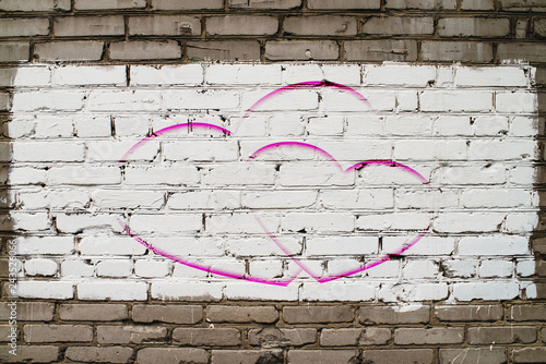 Two drawn hearts on brick wall with white paint close-up. Mock up. Urban background with two painted hearts. Imperfect exterior with love symbol graffiti. Valentine day image. Unideal brickwork.