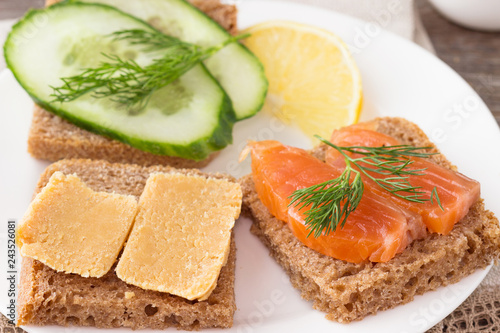 Traditional Norwegian breakfast, sandwiches with brown cheese brunost, sandwiches with cucumber and trout.