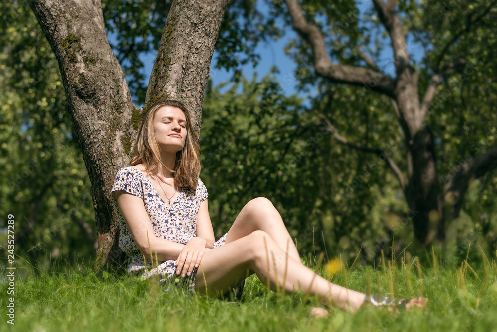 Attractive young woman resting under a tree in the spring garden Attractive young woman resting under a tree in the spring garden