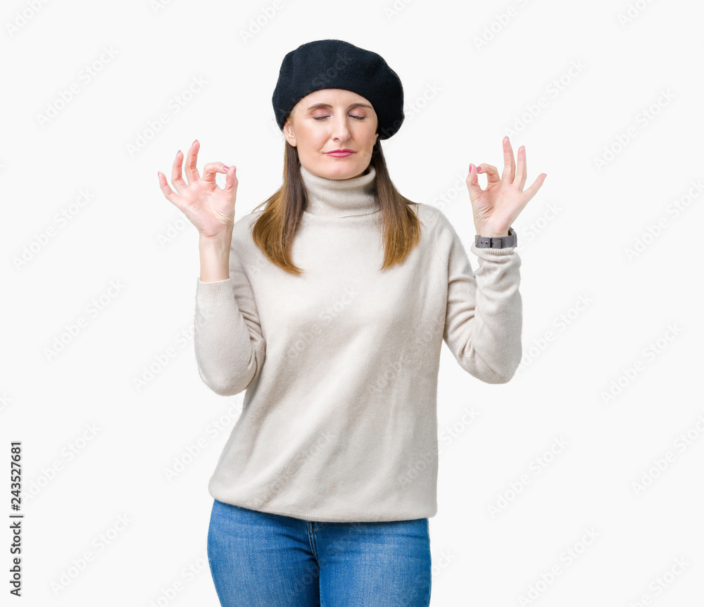 Middle age mature woman wearing winter sweater and beret over isolated background relax and smiling with eyes closed doing meditation gesture with fingers. Yoga concept. Middle age mature woman wearing winter sweater and beret over isolated background relax and smiling with eyes closed doing meditation gesture with fingers. Yoga concept.