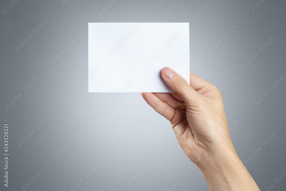 Male hand holding a blank card 10x15cm on gray background Male hand holding a blank card 10x15cm on gray background