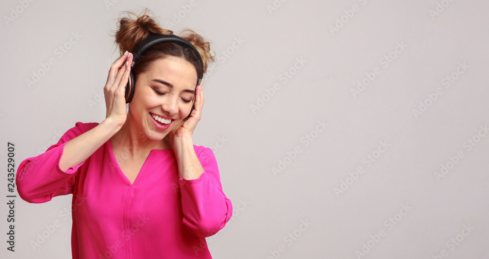 Happy woman enjoying music in headphones over background Happy woman enjoying music in headphones over background