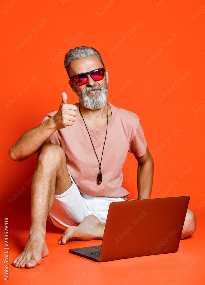 Full length portrait of a happy old man using laptop computer isolated over  orange background Stock-Foto | Adobe Stock