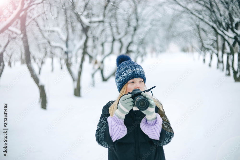 girl photographer in the winter in the snow-covered park photographs nature. woman in winter clothes. girl photographer in the winter in the snow-covered park photographs nature. woman in winter clothes.