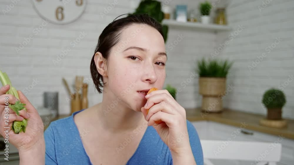 girl holds in hands eating raw celery and carrot at table girl holds in hands eating raw celery and carrot at table