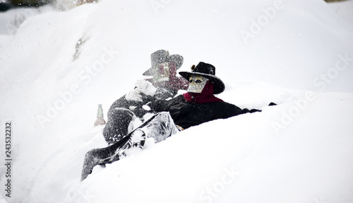 unrecognizable men wearing mask playing on snow