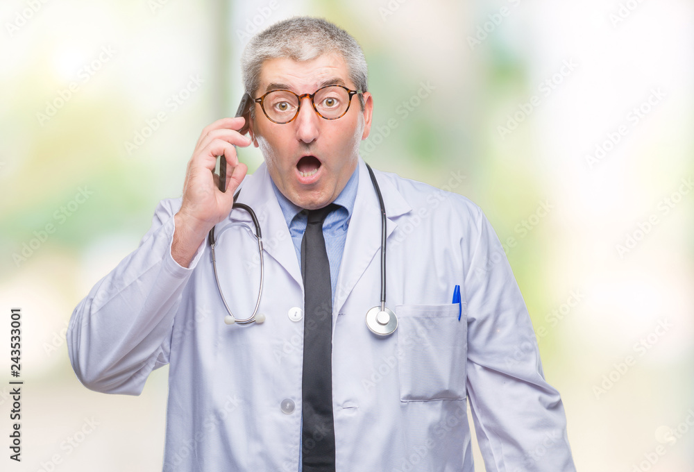 Handsome senior doctor man talking on smarpthone over isolated background scared in shock with a surprise face, afraid and excited with fear expression Handsome senior doctor man talking on smarpthone over isolated background scared in shock with a surprise face, afraid and excited with fear expression