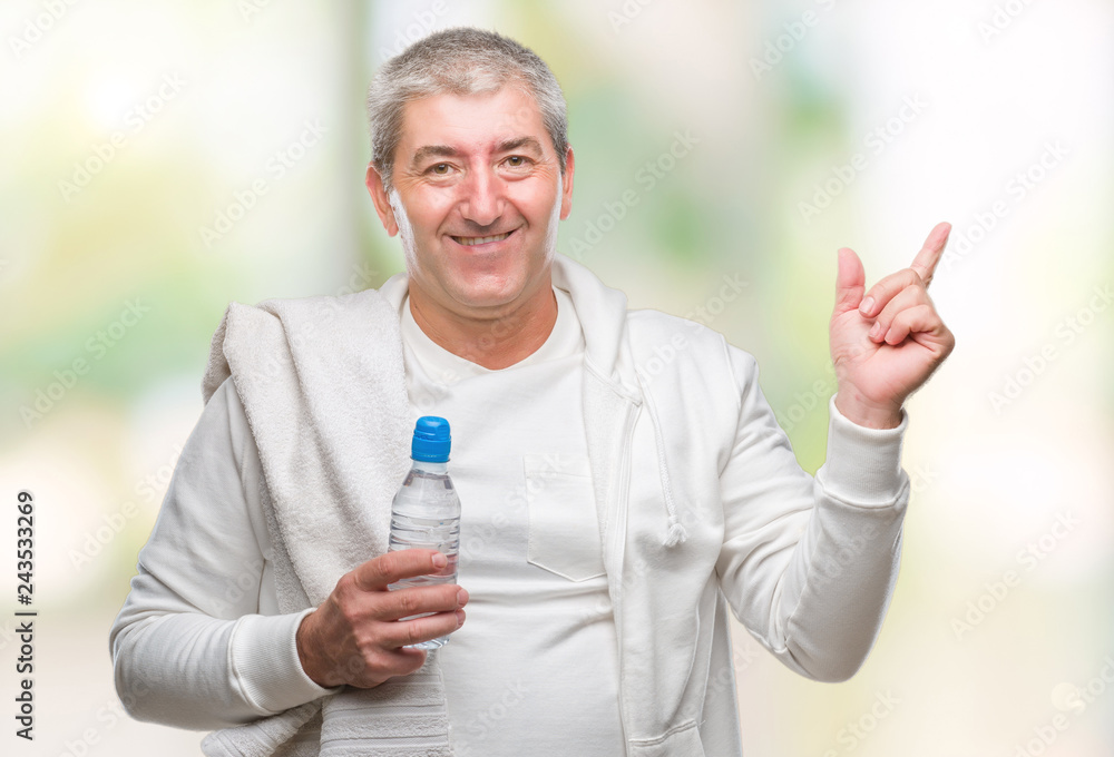 Handsome senior man training holding towel and water bottle over isolated background very happy pointing with hand and finger to the side Handsome senior man training holding towel and water bottle over isolated background very happy pointing with hand and finger to the side