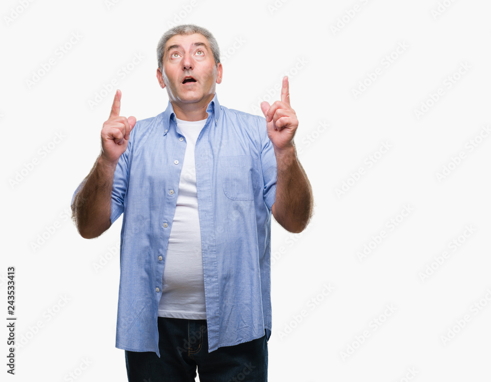 Handsome senior man over isolated background amazed and surprised looking up and pointing with fingers and raised arms. Handsome senior man over isolated background amazed and surprised looking up and pointing with fingers and raised arms.