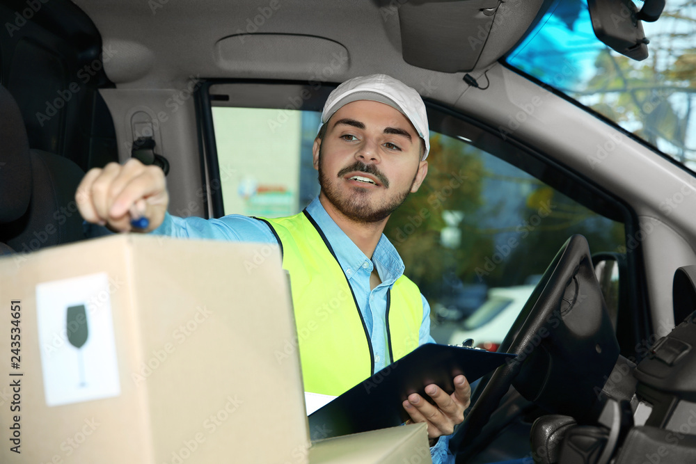 Young courier checking amount of parcels in delivery van Young courier checking amount of parcels in delivery van