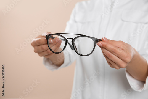 Female ophthalmologist with eyeglasses on light background, closeup. Space for text