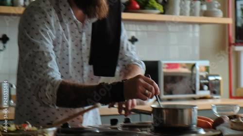 Wallpaper Mural A cheerful man cooks alone in the kitchen, enjoying the process. Watching the dish on the stove and making a salad. Man is cooking. Charismatic male hipster is cooking in the kitchen. Torontodigital.ca
