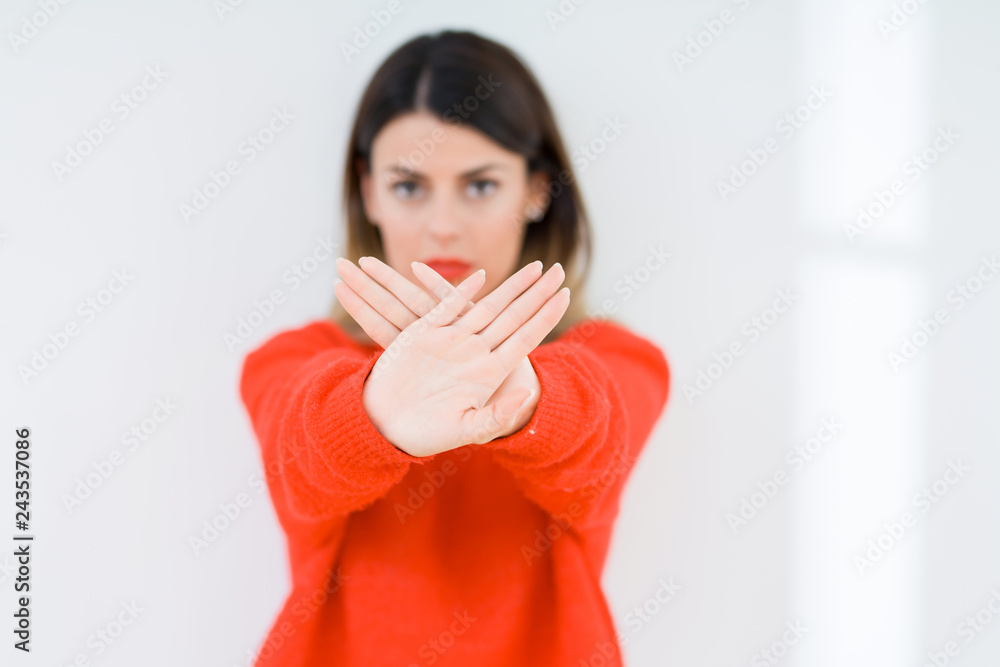 Young woman wearing casual red sweater over isolated background Rejection expression crossing arms and palms doing negative sign, angry face Young woman wearing casual red sweater over isolated background Rejection expression crossing arms and palms doing negative sign, angry face