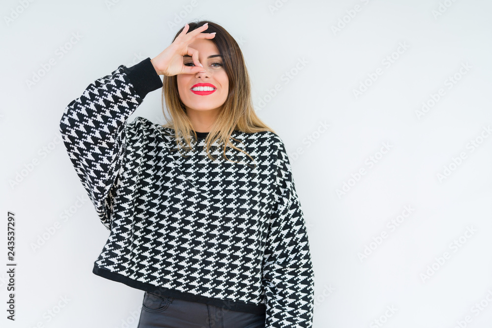 Young woman wearing casual sweater over isolated background doing ok gesture with hand smiling, eye looking through fingers with happy face. Young woman wearing casual sweater over isolated background doing ok gesture with hand smiling, eye looking through fingers with happy face.