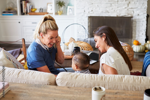 Female healthcare worker visiting a young mum and her infant son at home photo