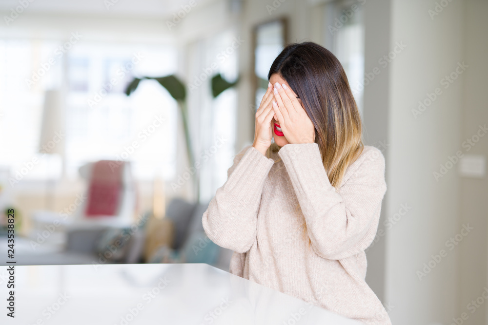 Young beautiful woman wearing winter sweater at home with sad expression covering face with hands while crying. Depression concept. Young beautiful woman wearing winter sweater at home with sad expression covering face with hands while crying. Depression concept.
