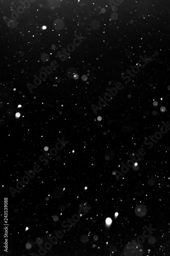 a bokeh of white snow on a black background