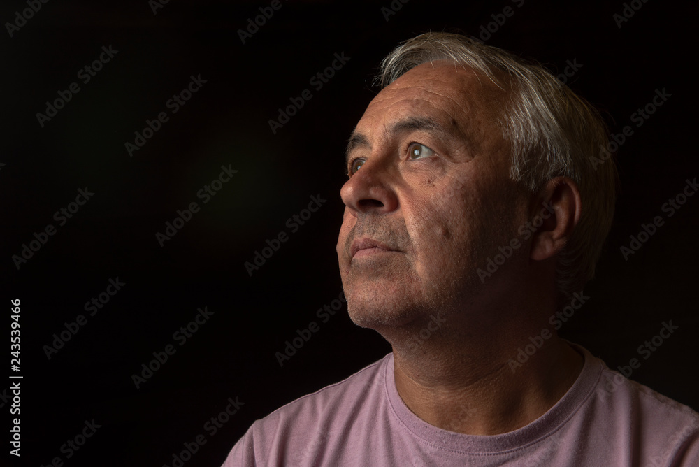 Dark portrait image of a mature man, with copy space 
