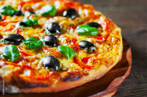 Pizza with Mozzarella cheese, Tomatoes, pepper, olive, Spices and Fresh Basil. Italian pizza. Pizza Margherita or Margarita on wooden table background