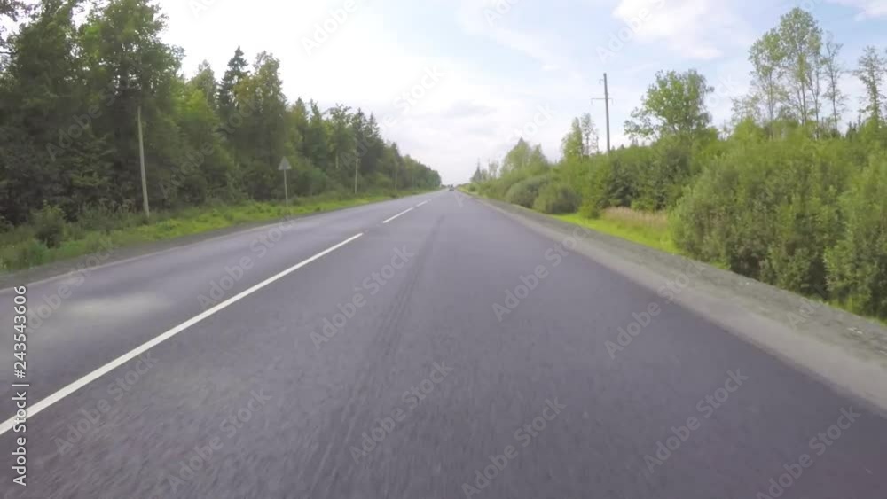 The car moves along the road along the forest on a summer day. Frontal view. The car moves along the road along the forest on a summer day. Frontal view.
