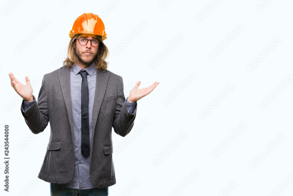 Young handsome architec man with long hair wearing safety helmet over isolated background clueless and confused expression with arms and hands raised. Doubt concept. Young handsome architec man with long hair wearing safety helmet over isolated background clueless and confused expression with arms and hands raised. Doubt concept.